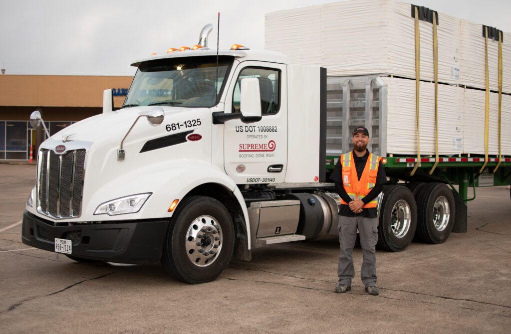 Man standing next to semi-truck with Supreme roofing logo on it.